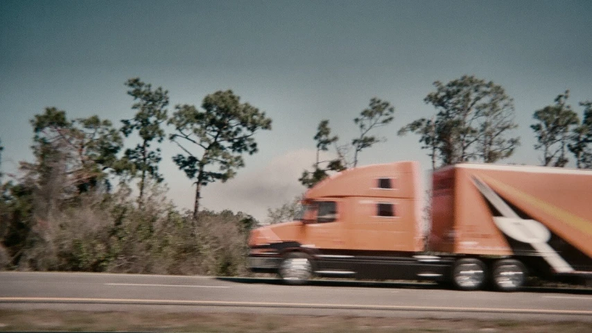 a large truck riding along the road between trees