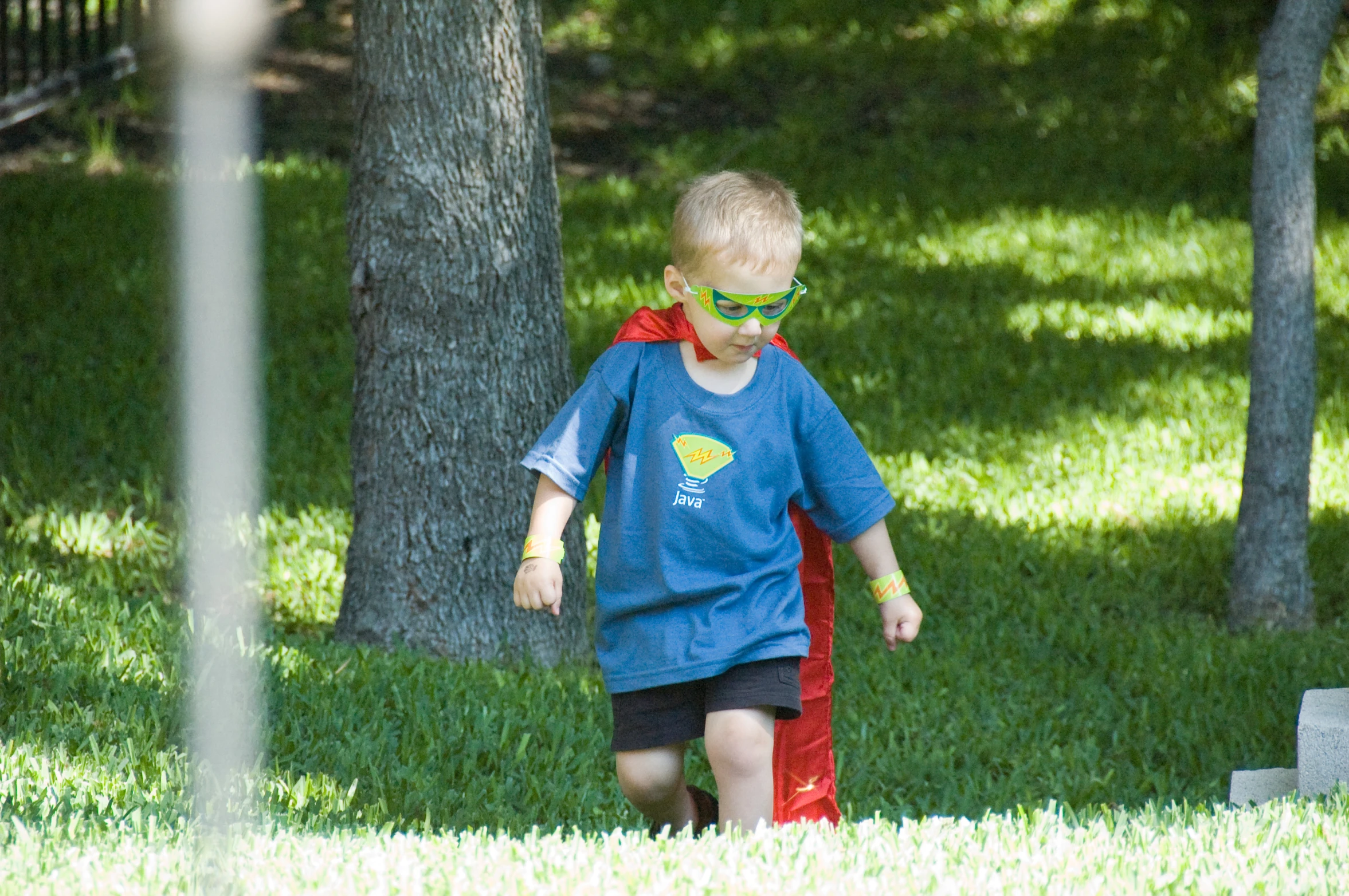 a  with goggles and a tee shirt on, walking across the grass