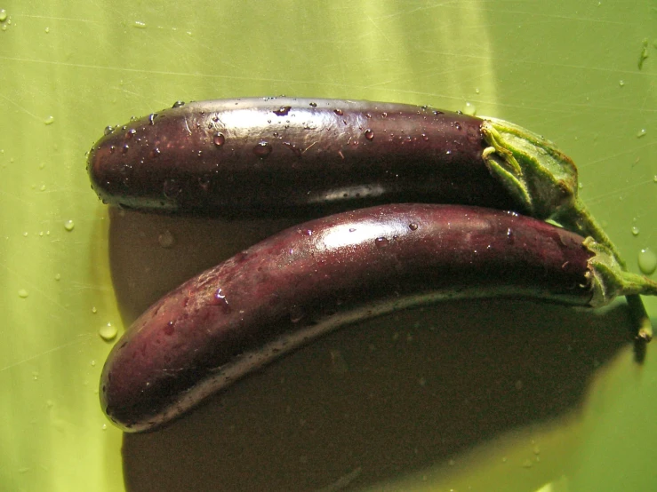 two eggplants on a surface with water droplets