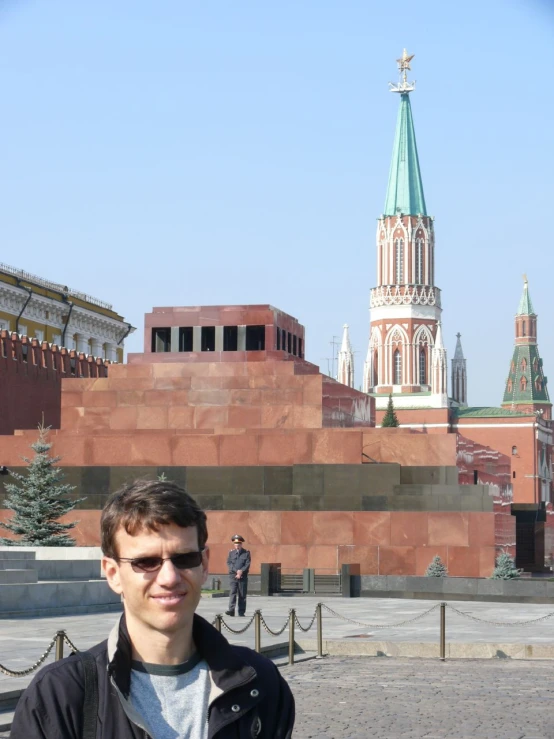 a man standing outside with a tower in the background