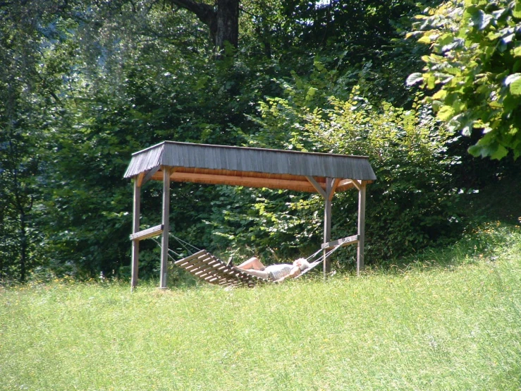 an empty hammock is sitting on grass in the middle of the park