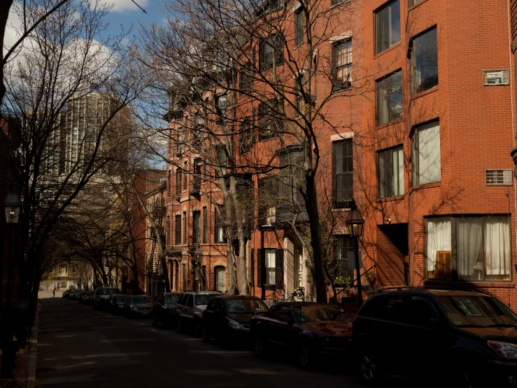 many buildings are along the street and two cars drive down the road