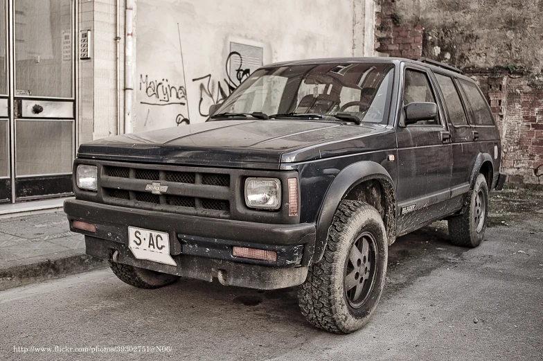 a truck parked by the curb near a building with graffiti on it