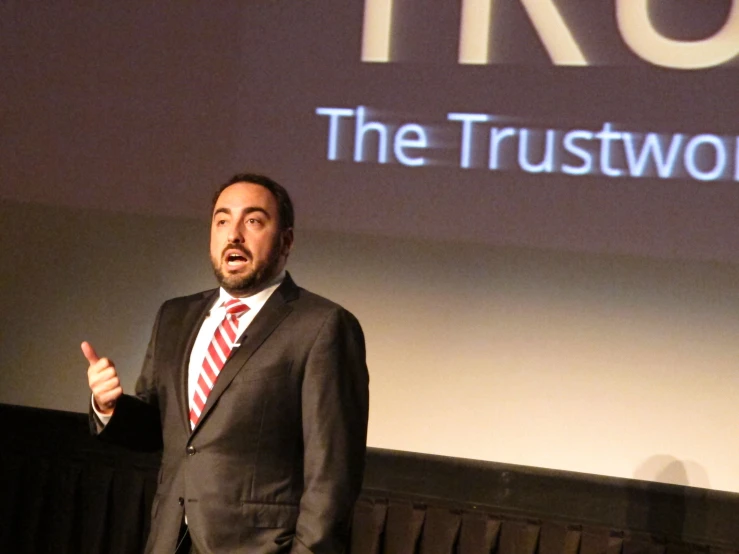 a man standing up in front of a large screen