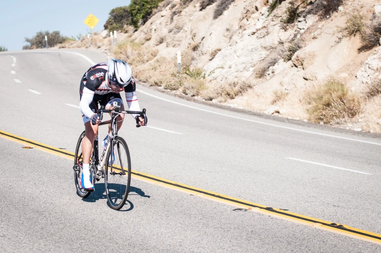 man riding bike with  on, and helmet partially tucked under his arms