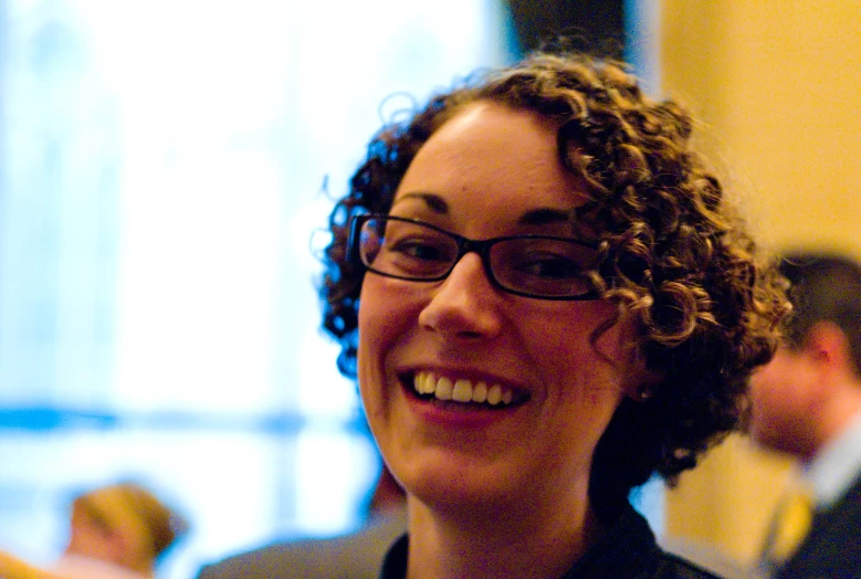 a woman wearing glasses smiling and having her hair clipped back