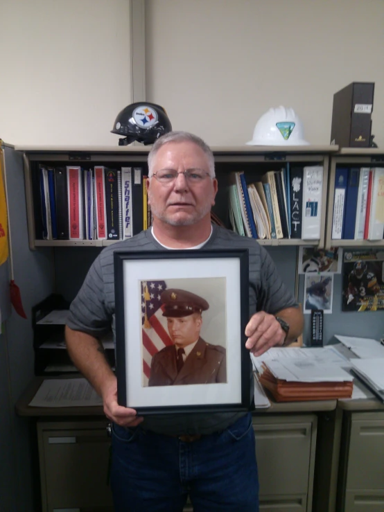 an older man holding up a picture of himself