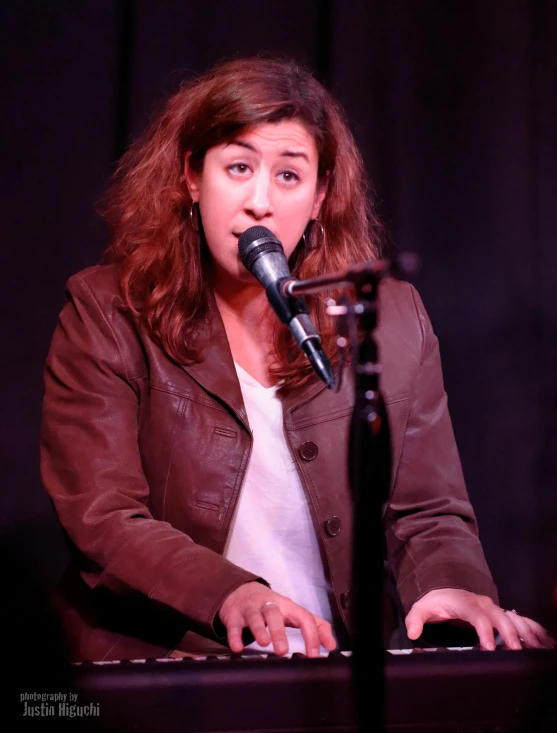 a woman standing in front of a microphone while playing a keyboard