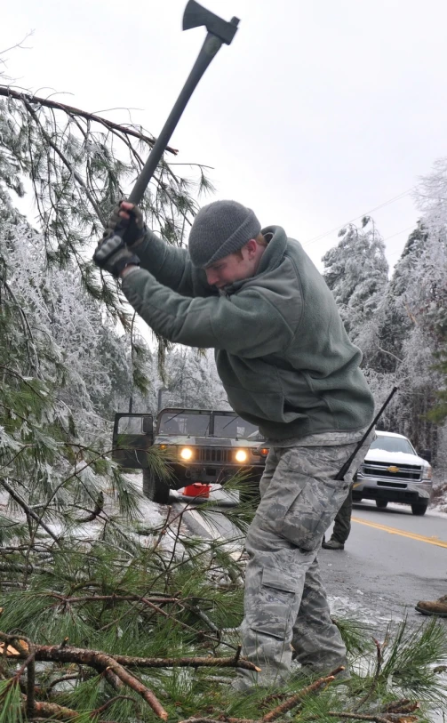 a man in camouflage with his hammer near fallen tree