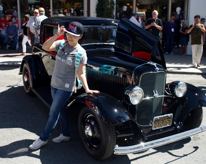 an older black car with a hood open at an automobile show