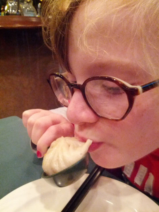 a woman eating soing on a spoon at a table