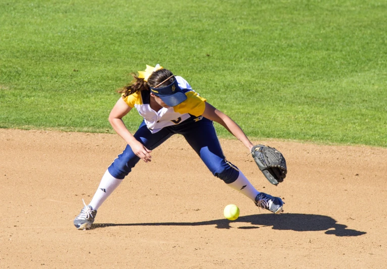 a girl in a softball uniform throwing the ball