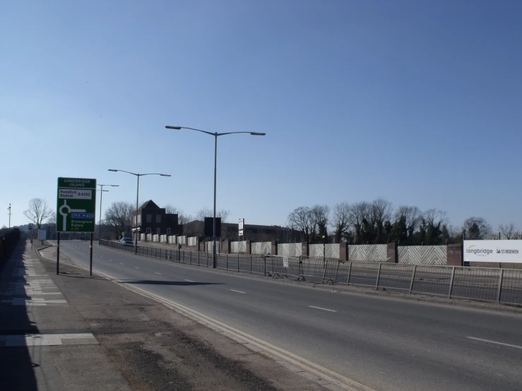 a empty street with a fence and large billboards in the distance