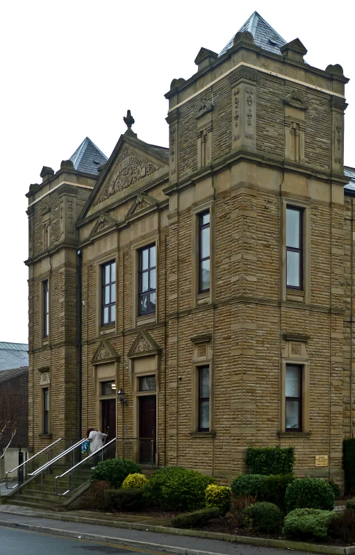 an old building has plants in front and a staircase leading up to it