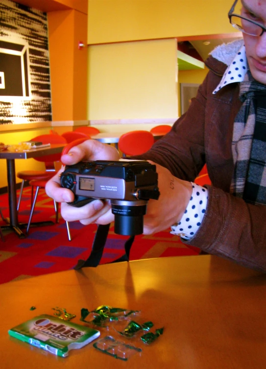 the man is holding a camera and assembling many pieces of circuit board