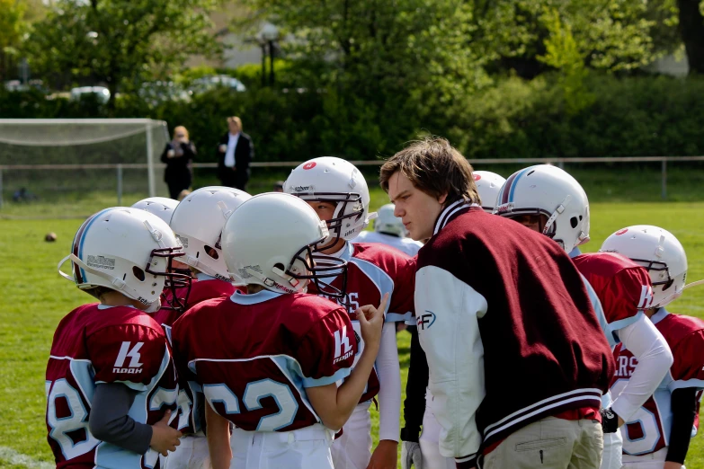 a coach speaking to his football team in a huddle