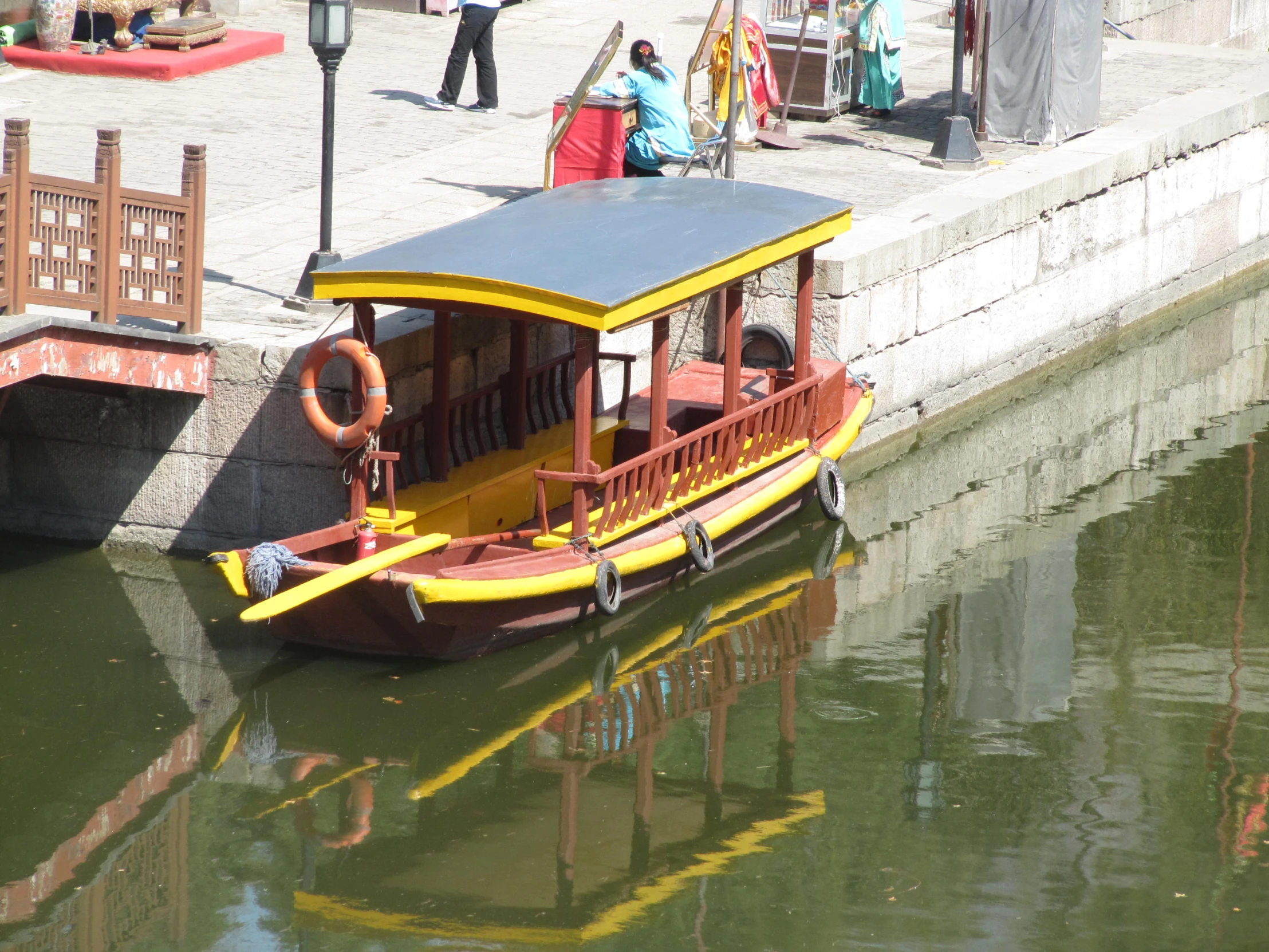 a little yellow boat in the water next to some people