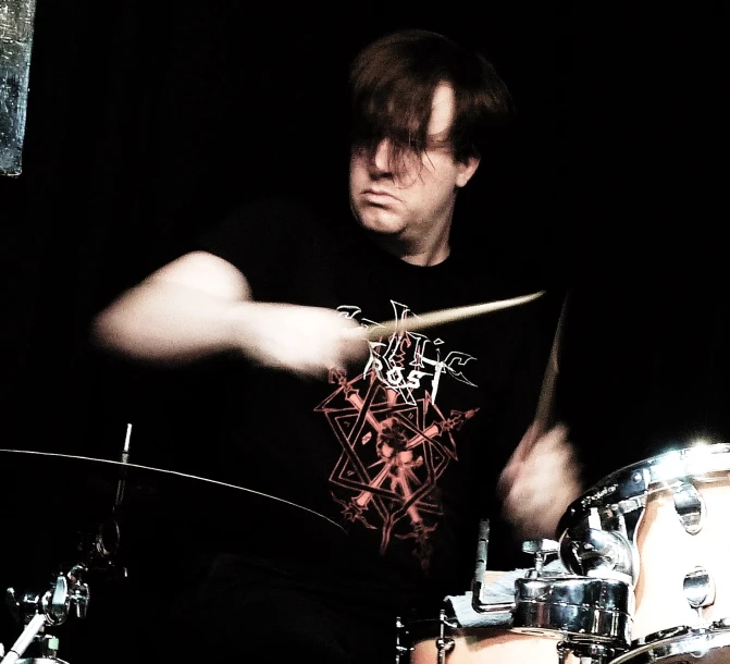 a man playing drums in front of dark backdrop