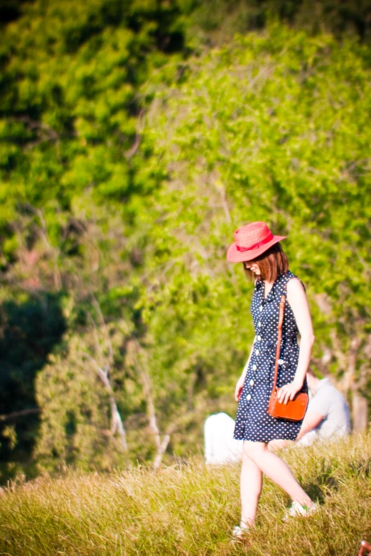 a woman walking down a dirt road through tall grass