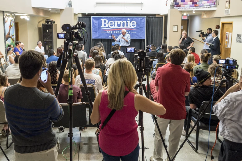 many people at a meeting with cameras set up