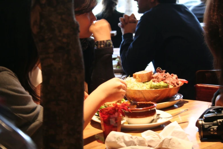 people sitting at a table eating food out of bowls