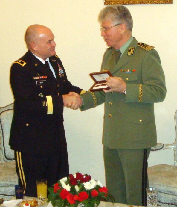 two military men in uniform shake hands