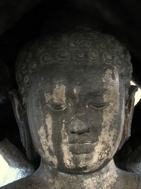 a head of a buddha statue with one eyes closed