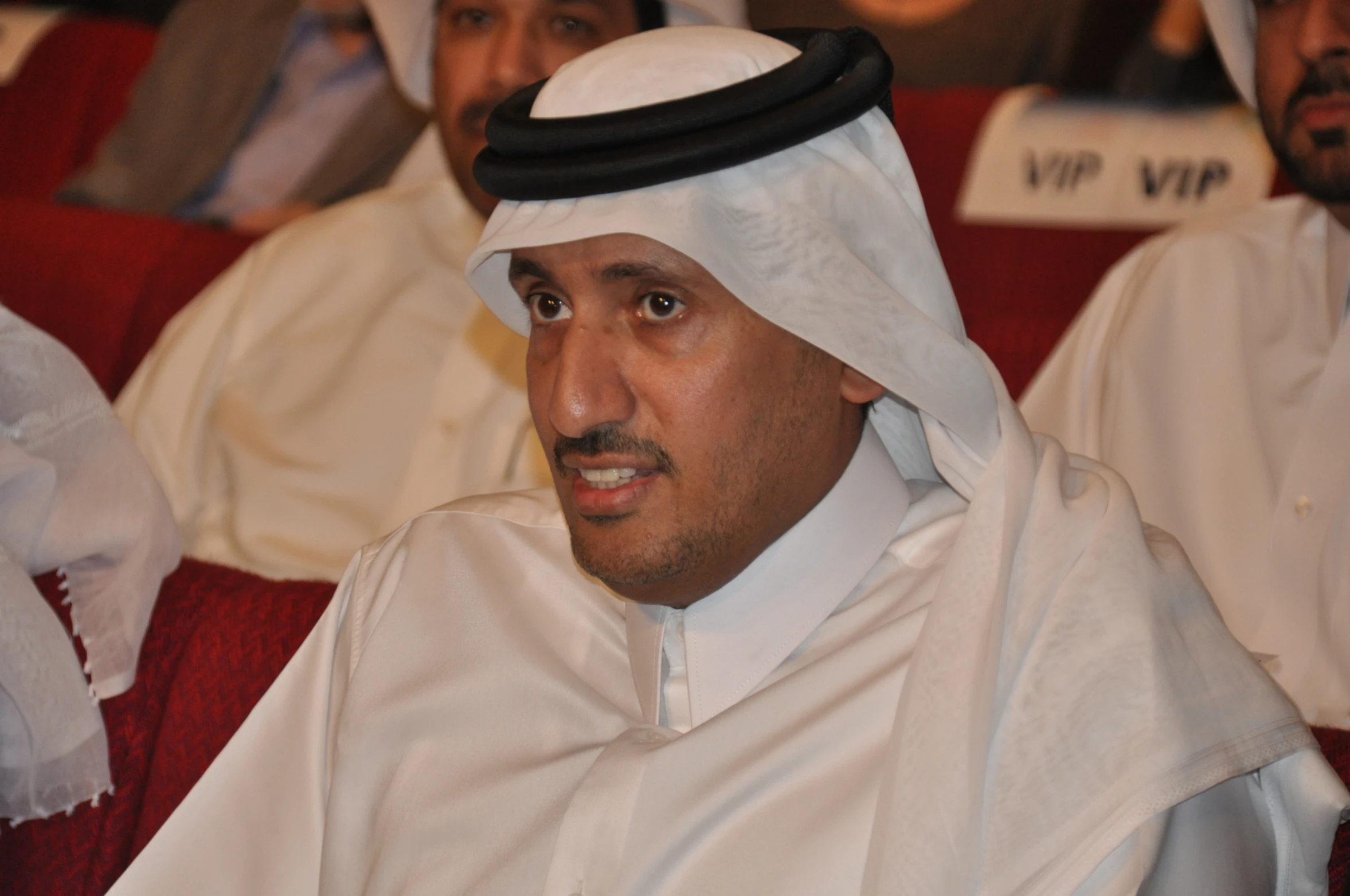 a man in white sits at the front of an audience