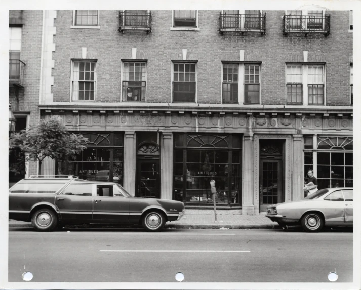 old time po of a shop front and cars parked in front