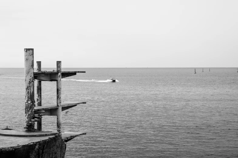 a boat is sailing in the distance behind an old pole