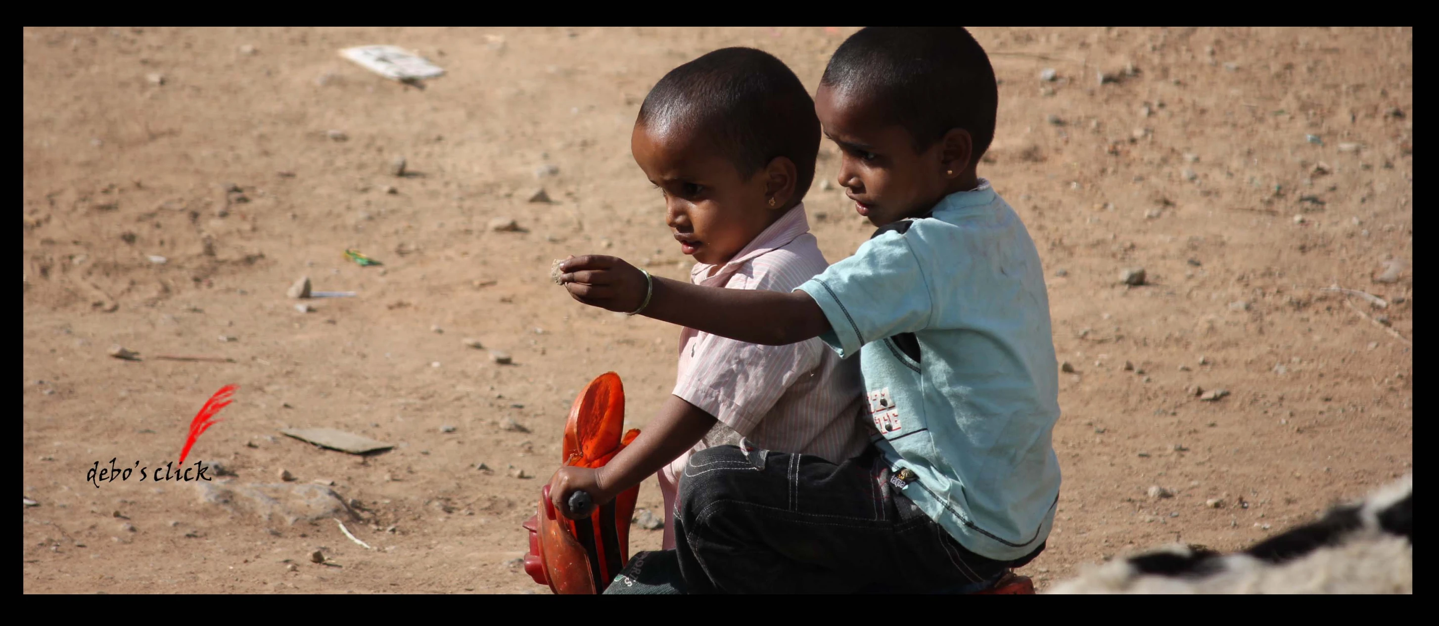 two small children are standing together in the dirt