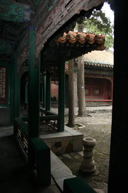 an outdoor covered area with benches, lanterns, and trees
