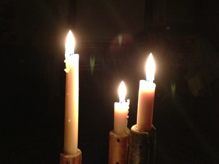 three lit candles in the dark in a room