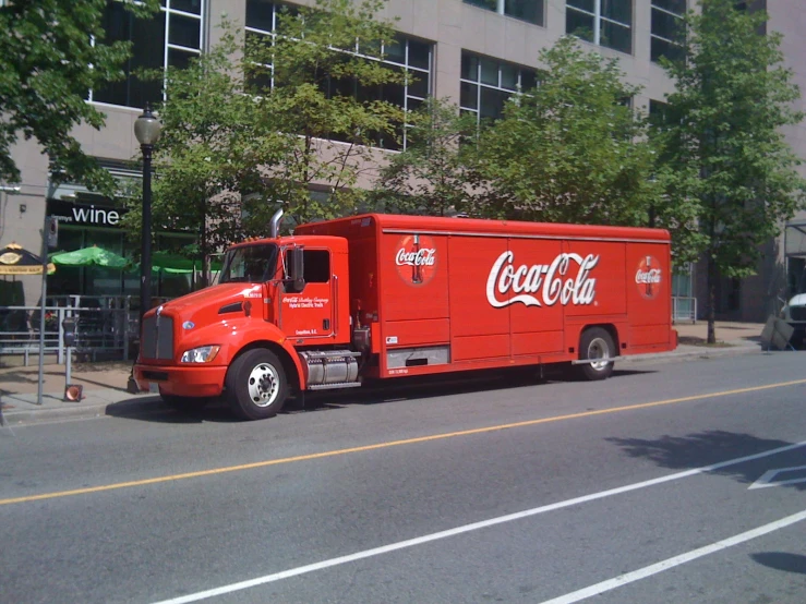 a coca - cola truck parked in front of a tall building