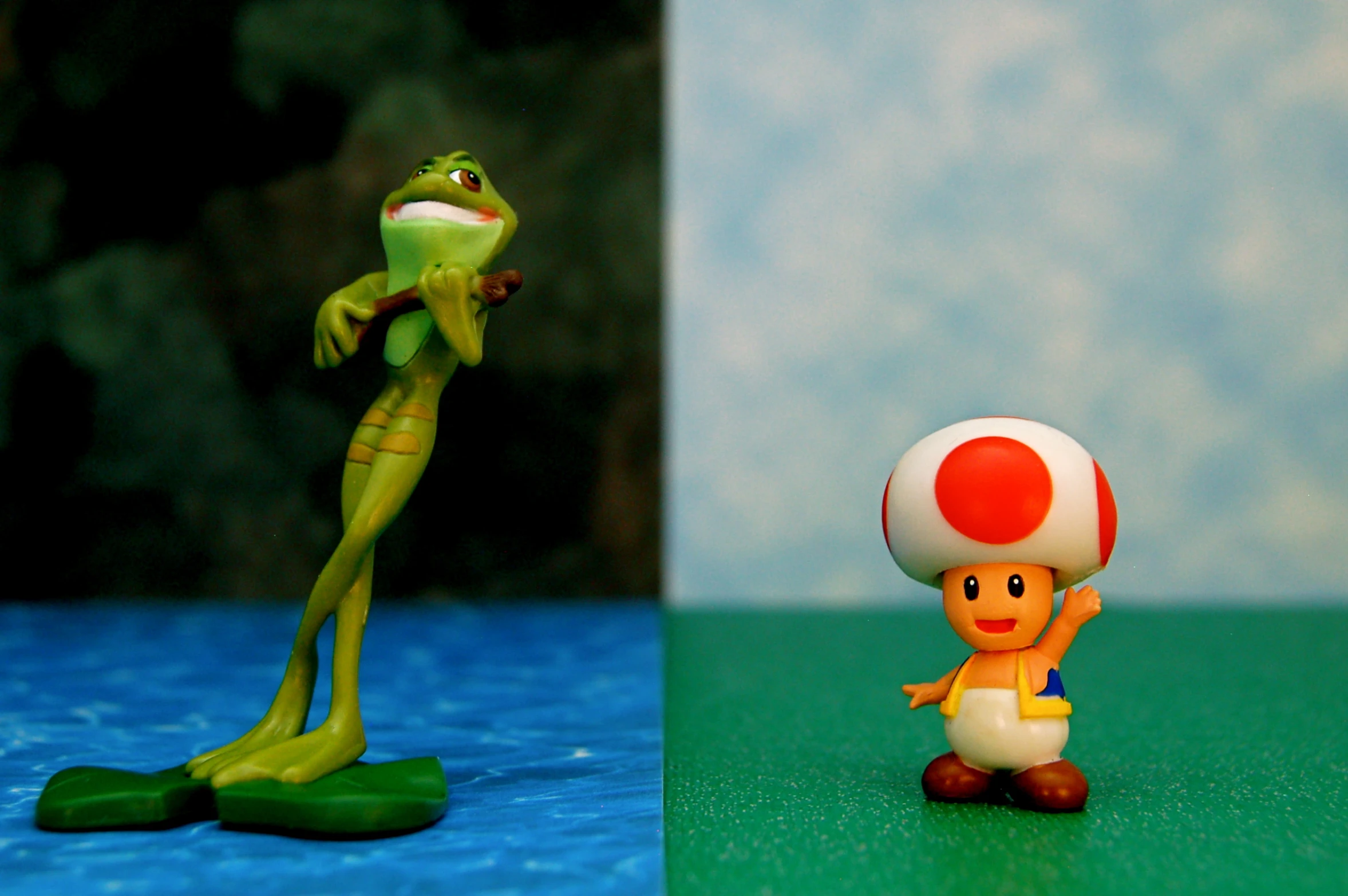 two toy figurines on blue and green background with frog