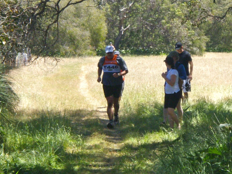 three people hiking in the grass with hats on