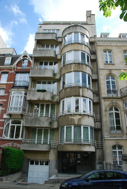 a tall building with many balconies next to a car