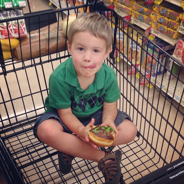 the boy in the store is eating his donut