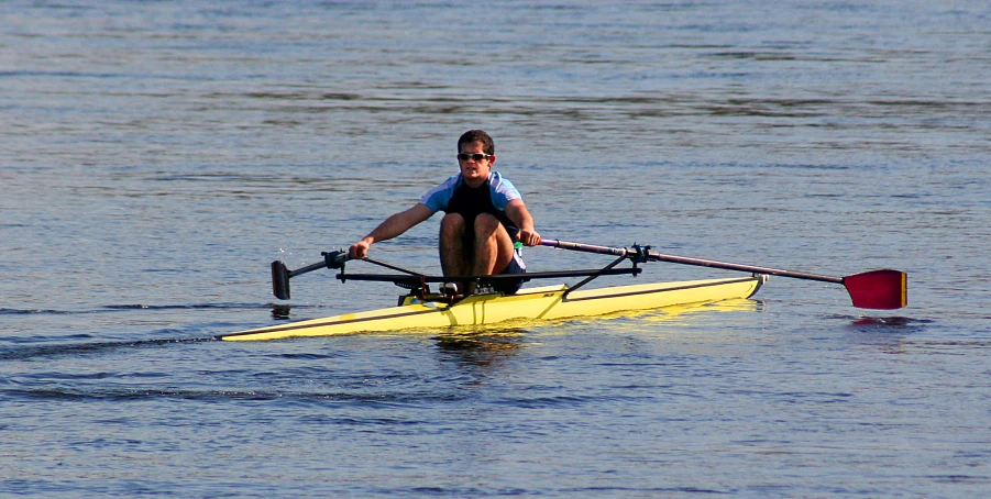 an adult rowing in a single boat on a river