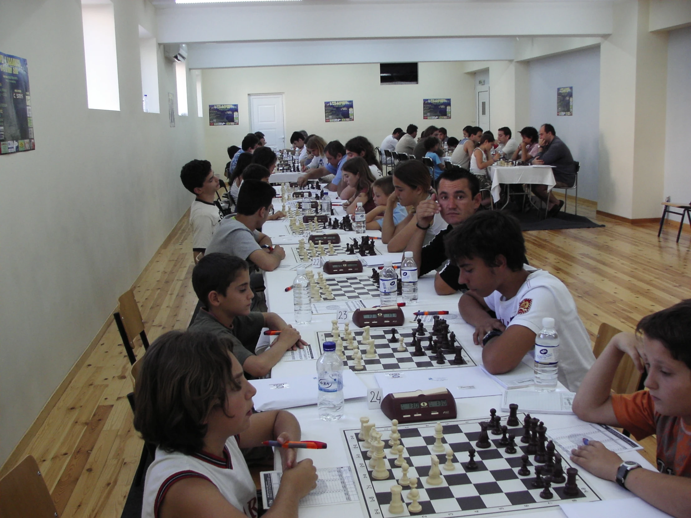 children playing chess in a playroom as adults watch