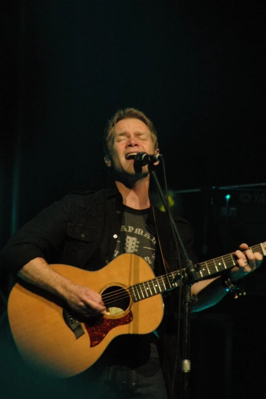 a man playing a guitar while standing in front of a microphone