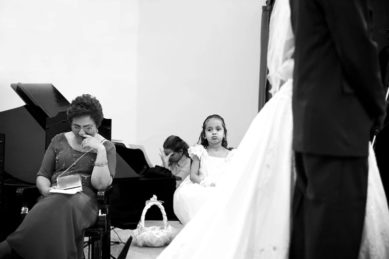 a bride in her dress looking at her daughter who is reading her book