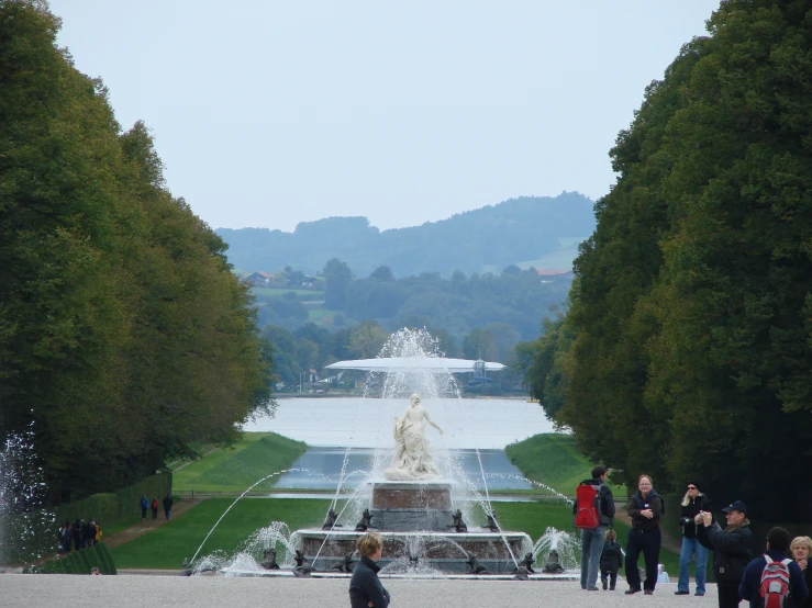 people at a fountain with mountains in the background