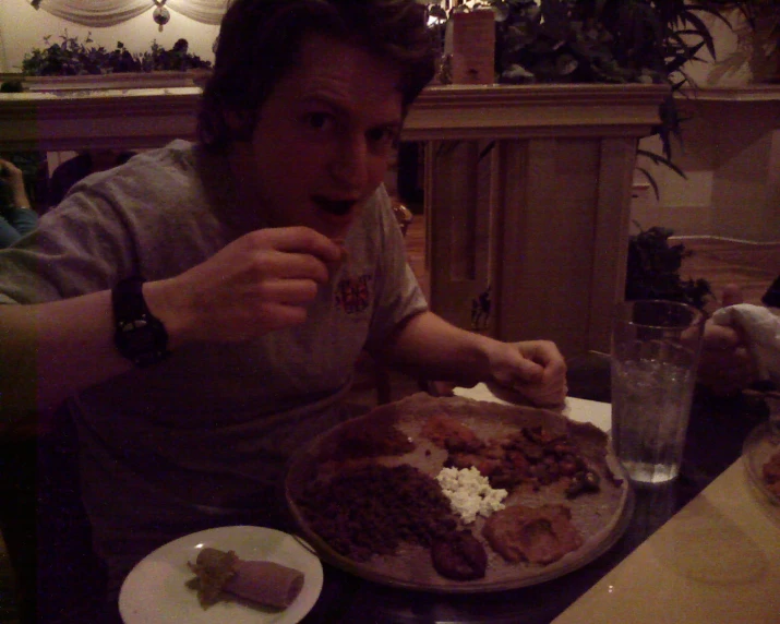 a man eating a plate with meats on it