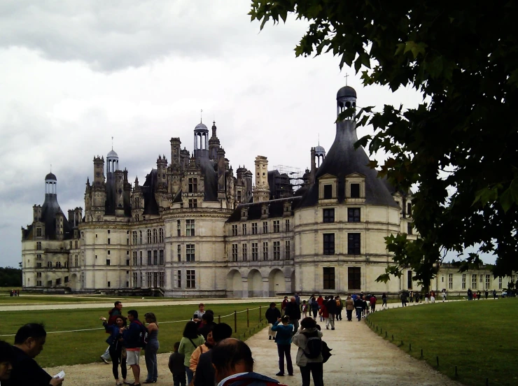 many people walking in front of a very old castle