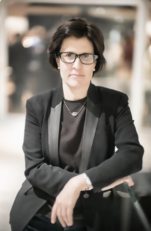 a woman sitting down wearing a suit and tie