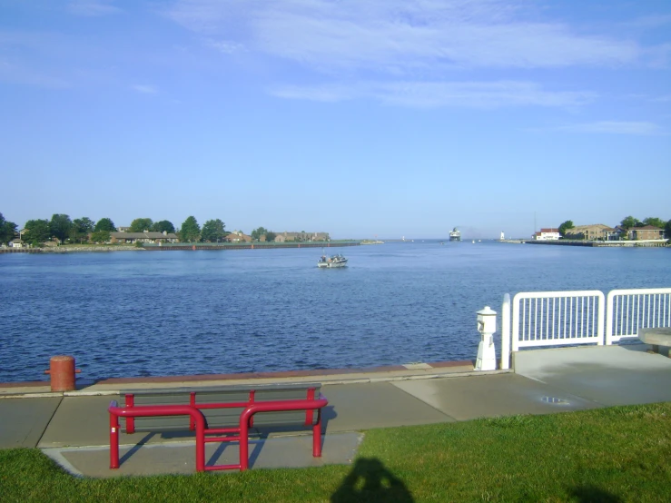 a blue lake has two red benches next to it