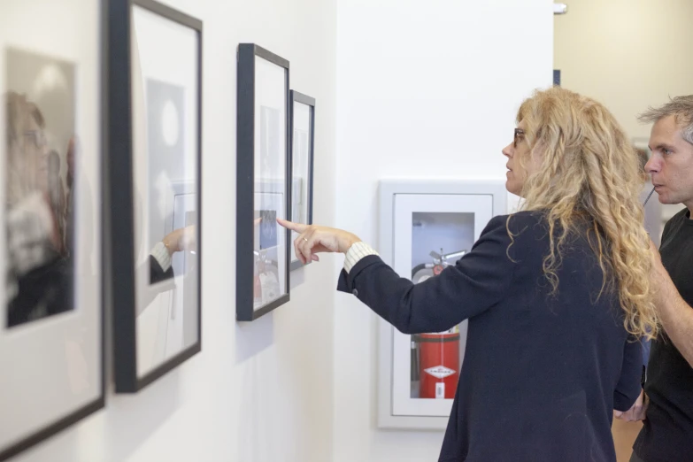 there are two people hanging pictures on the wall