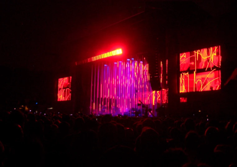 bright lights glow on the screen and curtain behind a large crowd