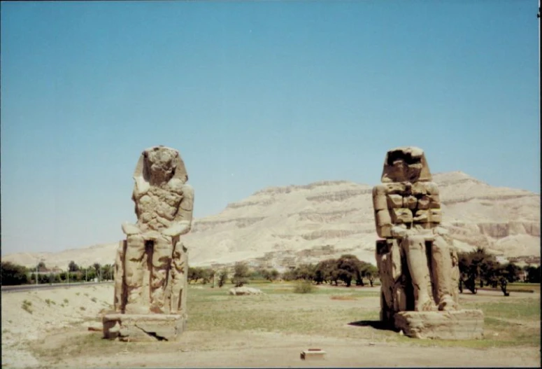 a large statue of two human like people near a field